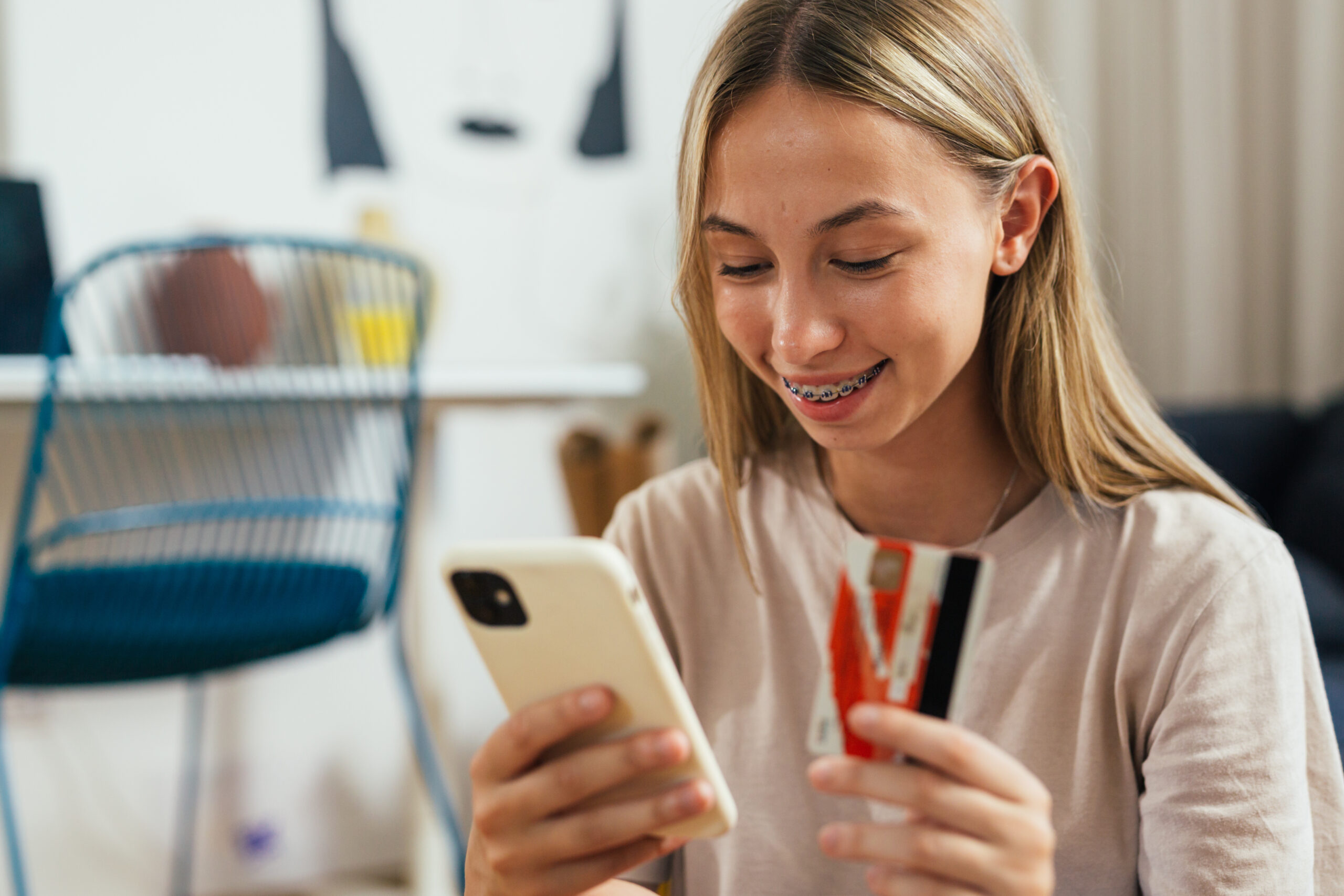 teen girl using a debit card to buy something on her phone.