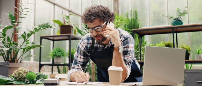 small business owner happily evaluates loan options on the phone while at desk