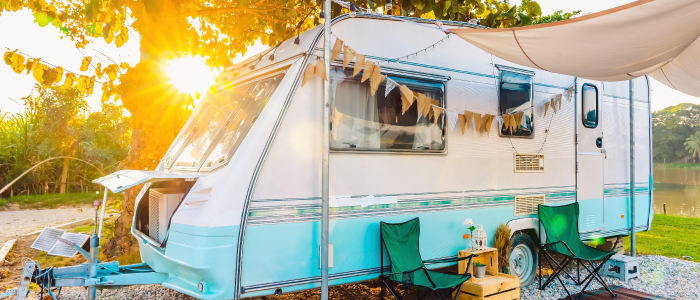 Shiny retro travel trailer sits peacefully at camp under the setting sun.  